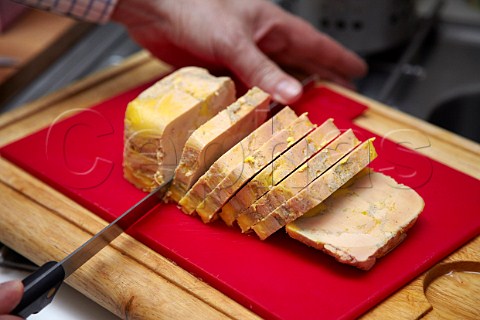 Man slicing foie gras in his kitchen Paris France