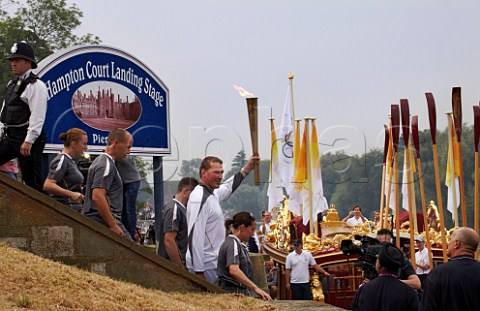 Friday 27 July 2012 Sir Matthew Pinsent carrying the Olympic torch to the Gloriana rowbarge on the River Thames at Hampton Court on which it will be carried to London The rowers are holding their oars aloft  England
