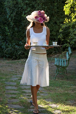 Young woman carrying tray of tea in garden Tuscany Italy