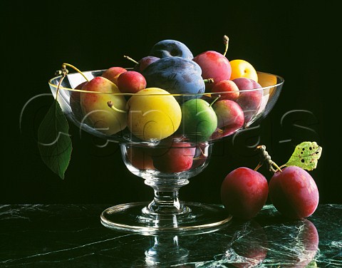 Different varieties of plums in a glass bowl
