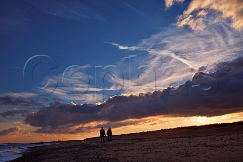 Couple walking along beach at dusk Southwold Suffolk England