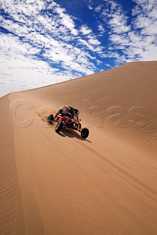 Baja 1000 race car belonging to The Gentleman Driver company negotiating a sand dune in the Atacama Desert Chile