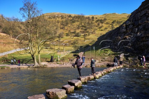 People on the famous Stepping Stones across the River Dove Dovedale Derbyshire England  Peak District National Park