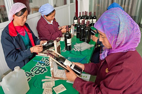 Women labelling bottles of Jia Bei Lan by hand at HeLan Qing Xue Winery Yinchuan Ningxia Province China