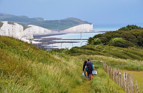 People going for a picnic at Seaford Head with the Seven Sisters beyond Sussex England