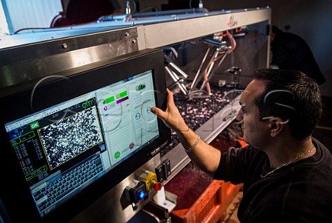 Technician operating Alien a robotic triage machine for sorting grapes Chteau HautBailly Lognan Gironde France PessacLognan  Bordeaux