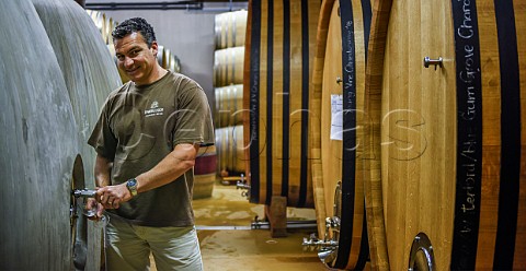 Carl van der Merwe winemaker tasting wine from a concrete egg in cellar of DeMorgenzon Stellenbosch Western Cape South Africa