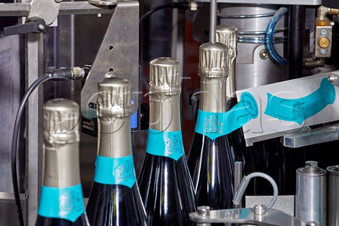 Machine applying neck labels to bottles of Wiston Estate sparkling wine  Washington Sussex England