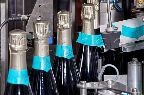 Machine applying neck labels to bottles of Wiston Estate sparkling wine  Washington Sussex England