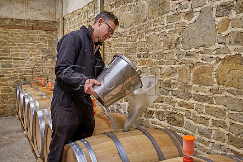 Simon Woodhead winemaker filling new oak barrel with Chardonnay must in winery of Stopham Estate Stopham Sussex England