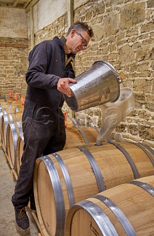 Simon Woodhead winemaker filling new oak barrel with Chardonnay must in winery of Stopham Estate Stopham Sussex England