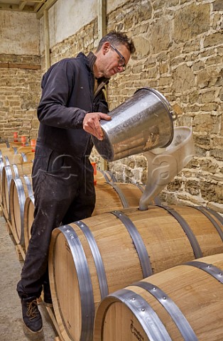 Simon Woodhead winemaker filling new oak barrel with Chardonnay must in winery of Stopham Estate Stopham Sussex England
