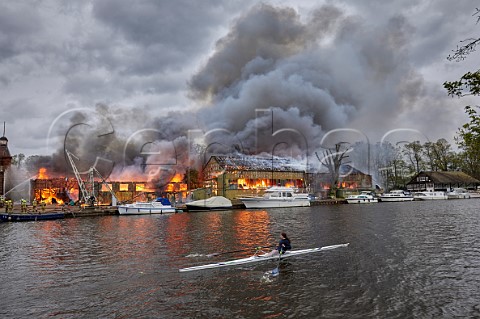 Rower from Wimbledon High School passing the Platts Eyot fire of 3 May 2021 which destroyed the boat shed of Otter Marine and the Dunkirk evacuation ship Lady Gay The River Thames at Hampton Middlesex England