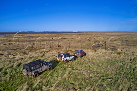 Land Rovers stop where the byway ends at the edge of the salt marshes Morston Greens Norfolk England