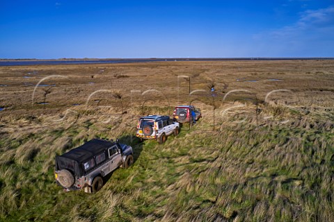 Land Rovers stop where the byway ends at the edge of the salt marshes Morston Greens Norfolk England