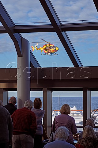 Passengers watch as a helicopter from the Scurit civile arrives to airlift a sick passenger to hospital on board the Saga Sprit of Discovery off the Brittany coast France